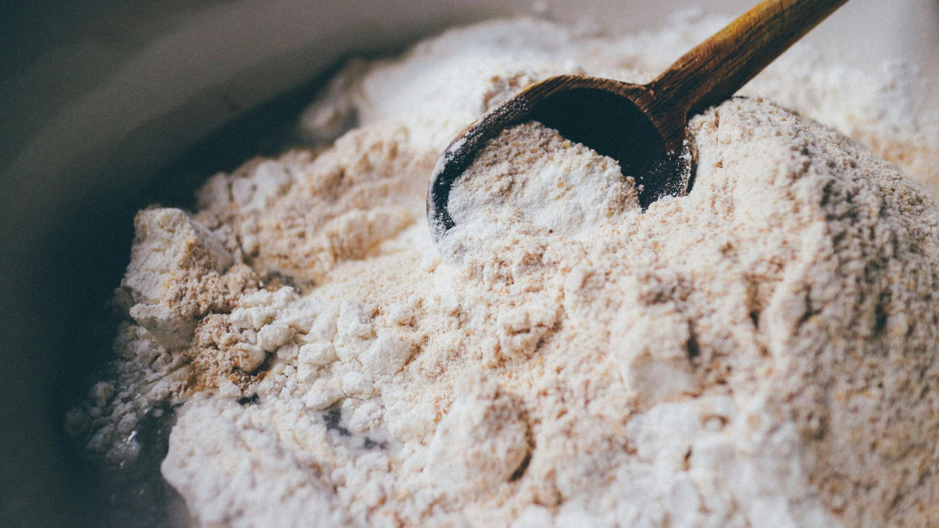 Wooden spoon scooping pile of flour