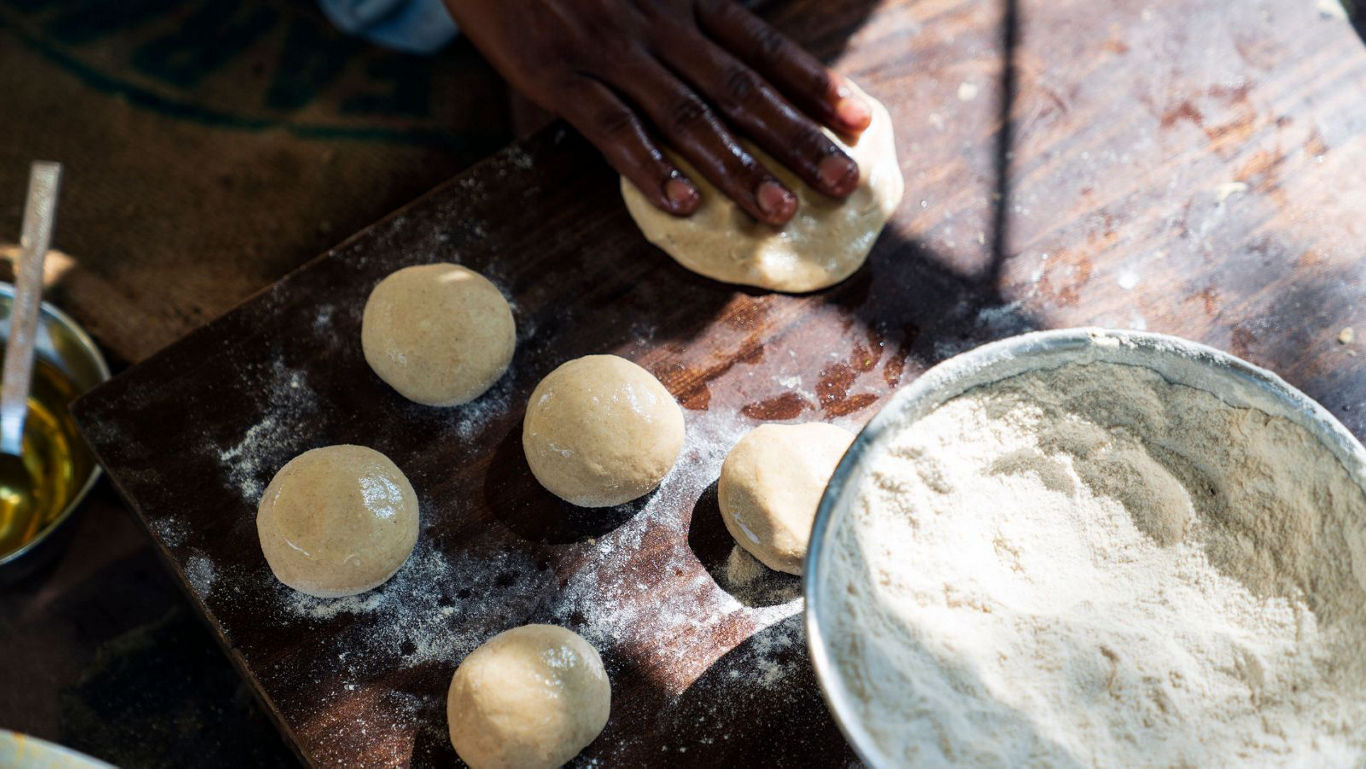 Hands kneading dough balls on wooden table