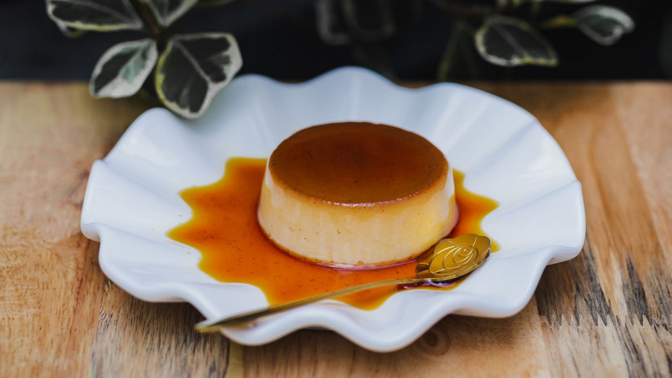 Caramel flan dessert on white scalloped plate