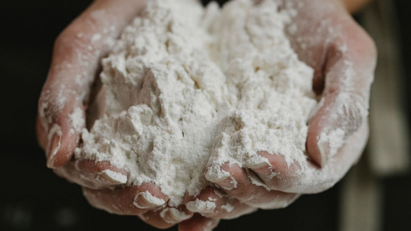 Hands holding a mound of white flour