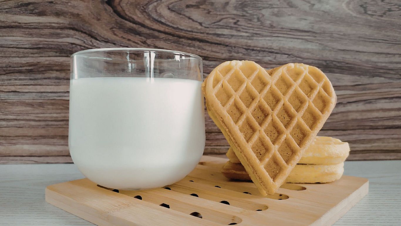 Glass of milk with heart shaped waffle