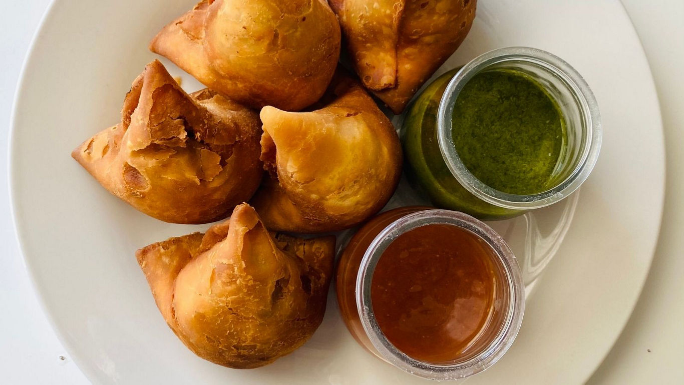 Plate of samosas with chutney dips