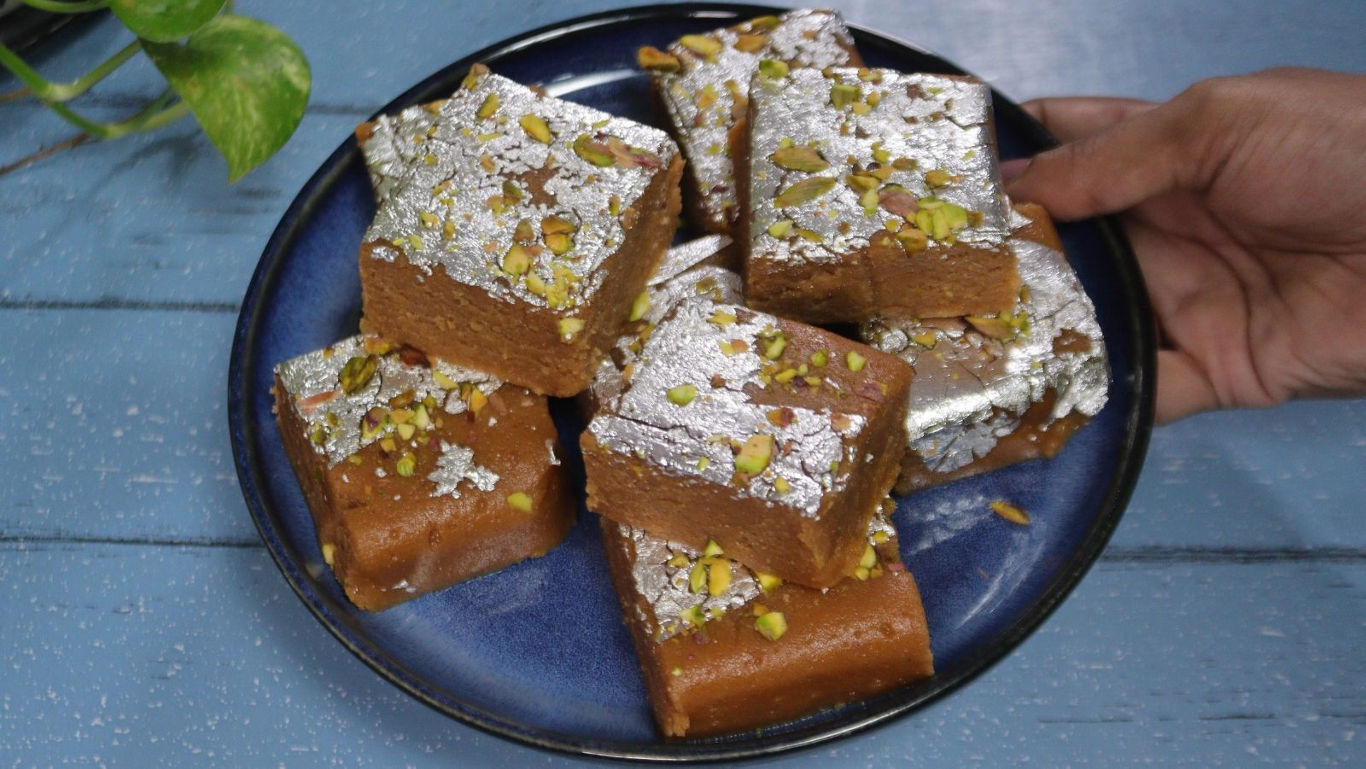 Hand serving plate of pistachio barfi sweets