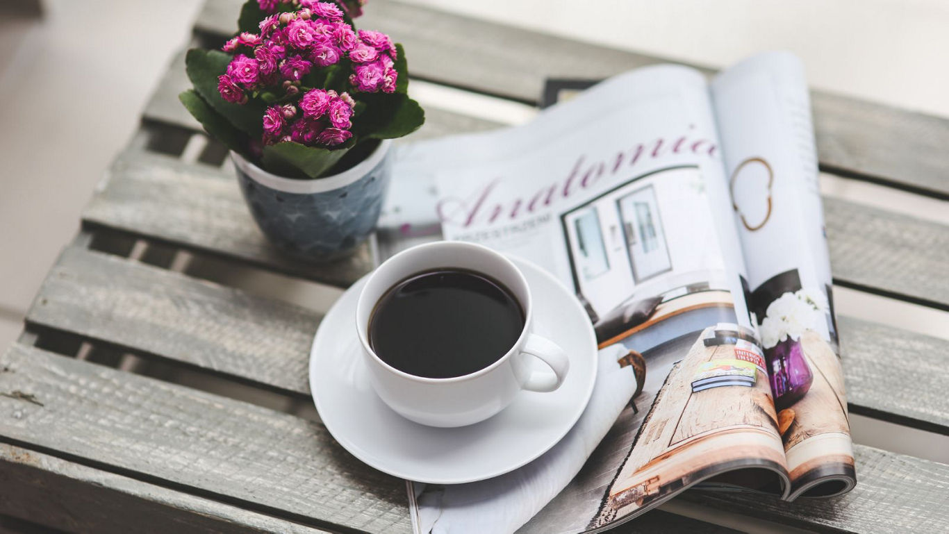 Coffee cup with magazine and flowers