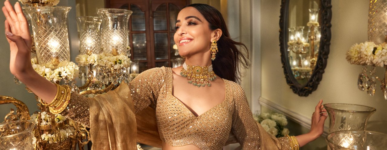 Elegant woman in golden sari showcasing opulent gold necklace and earrings