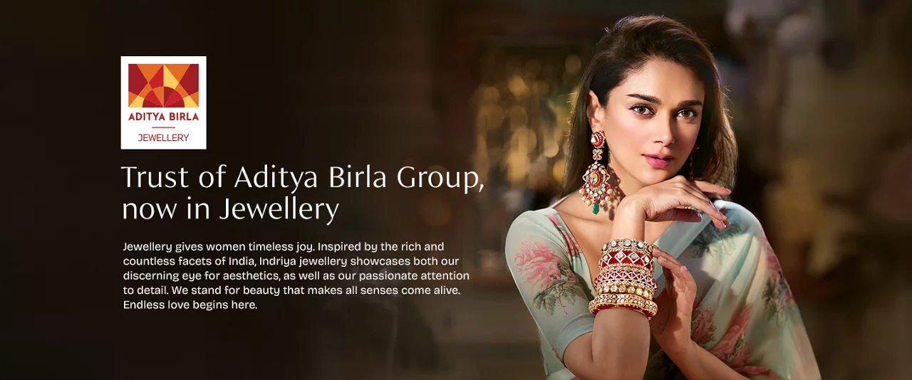 Elegant woman in emerald gold necklace and earrings from Aditya Birla Group