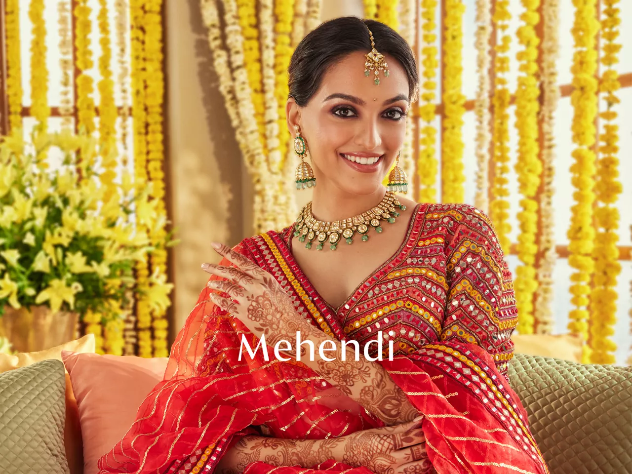 Woman in red mirror-work outfit with mehndi hands, gold jewellery, and "Mehendi" text.