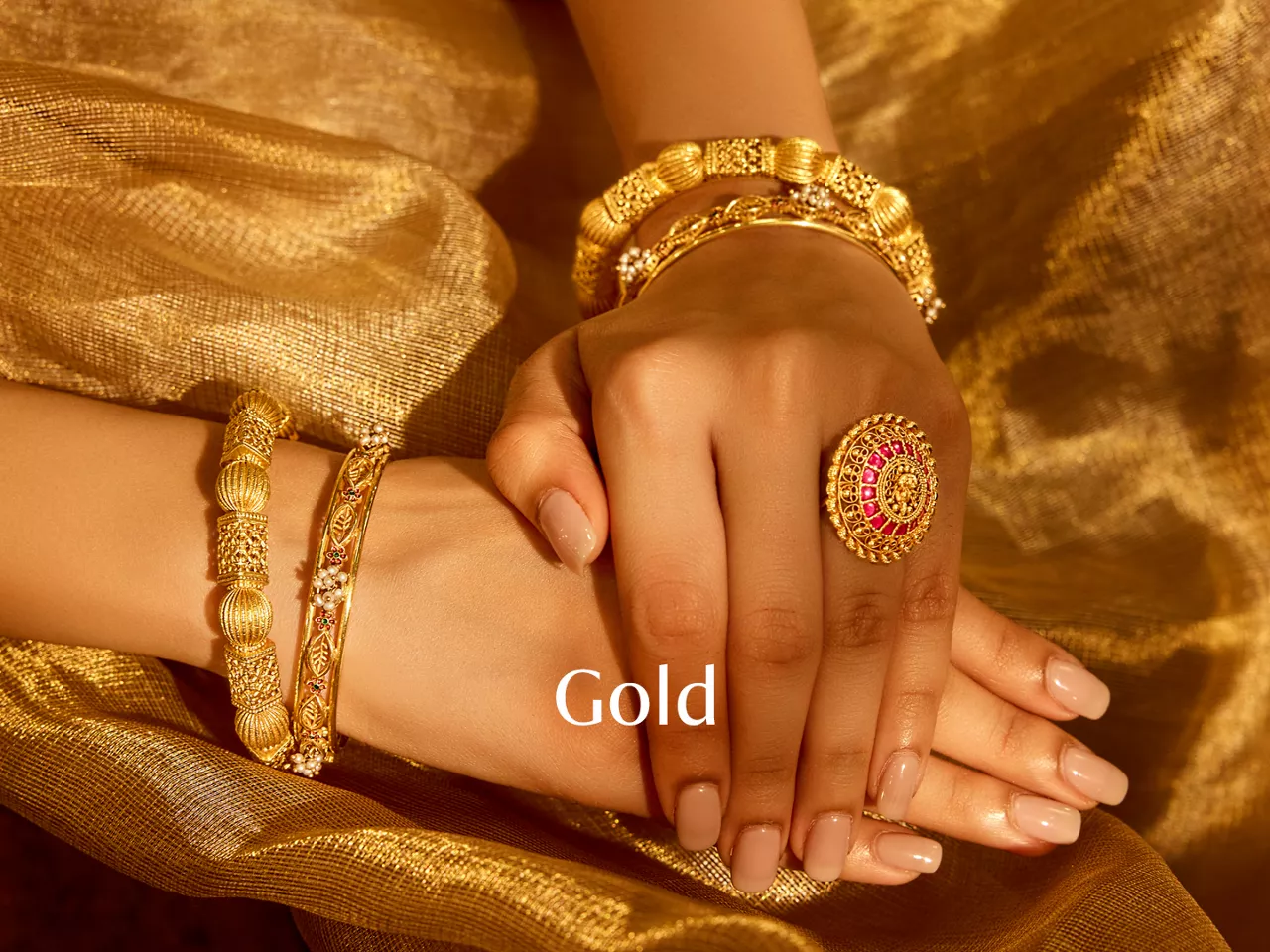 Gold bangles and ruby ring on women's hands with "Gold" text.