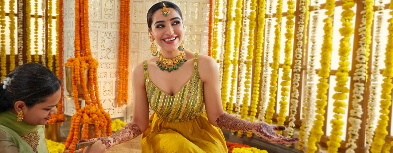 Bride in yellow outfit with green and gold jewellery