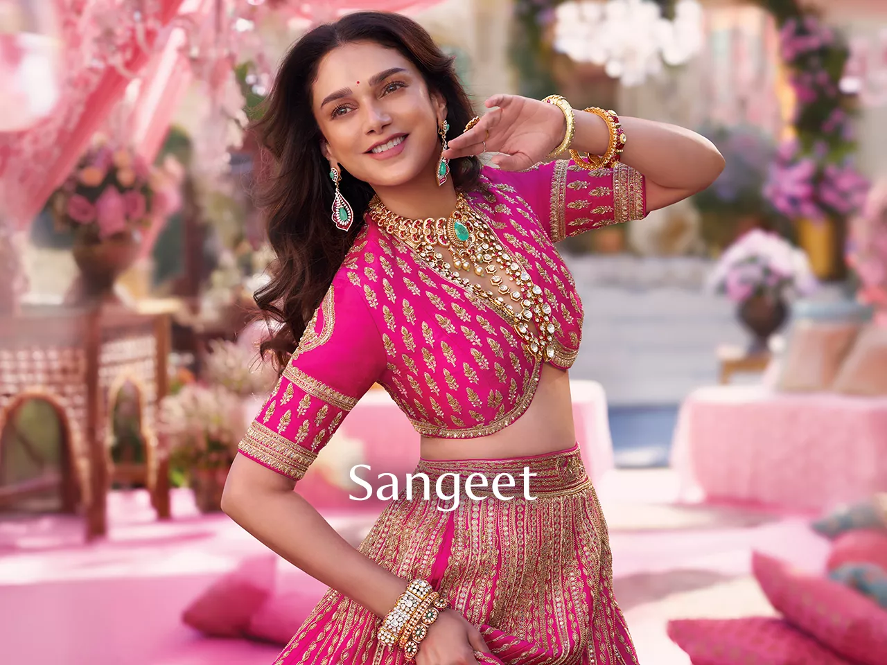 Woman in pink embroidered lehenga with gold jewellery and "Sangeet" text.