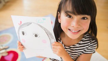 Filipino girl displaying drawing in bedroom