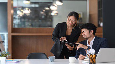 Two employees reviewing information on a tablet together