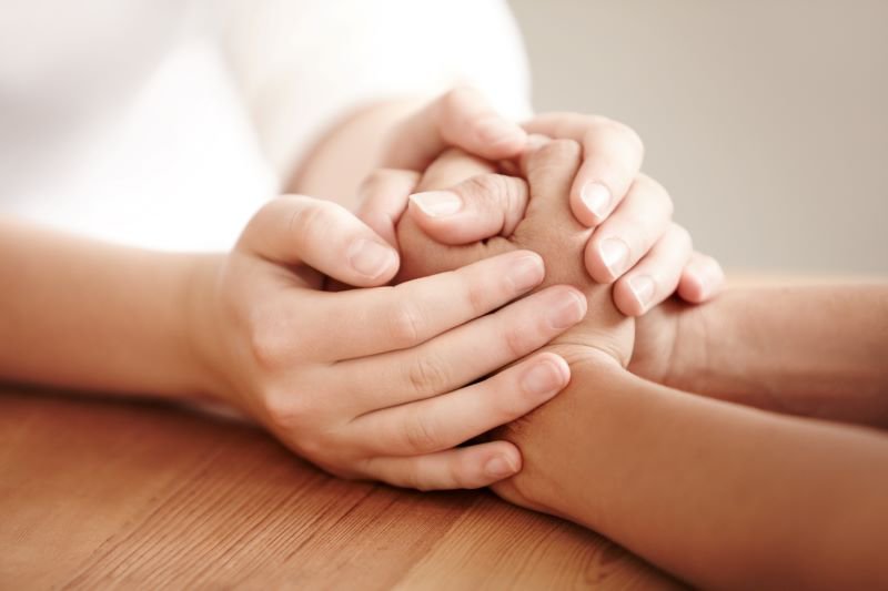 A close-up of a pair of hands enveloping another 