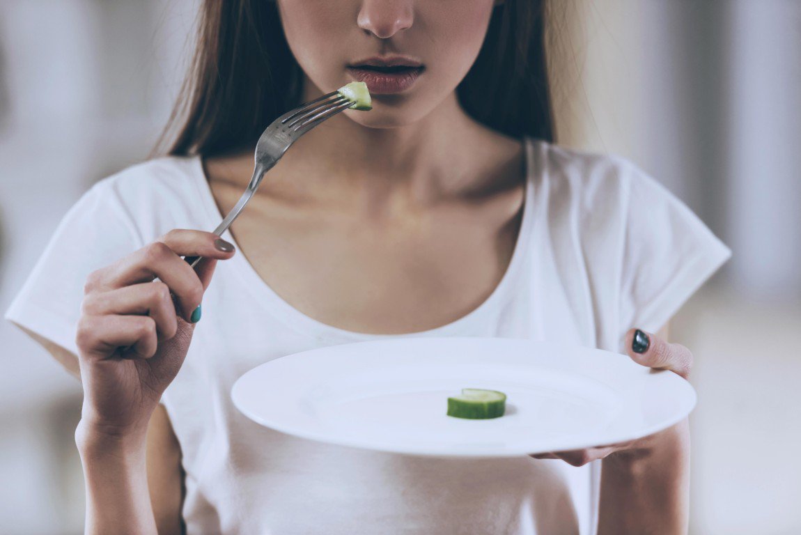 A woman holding a plate and a fork with a piece 