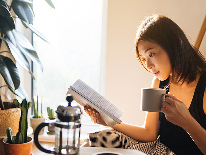 Girl reading a book while drinking coffee