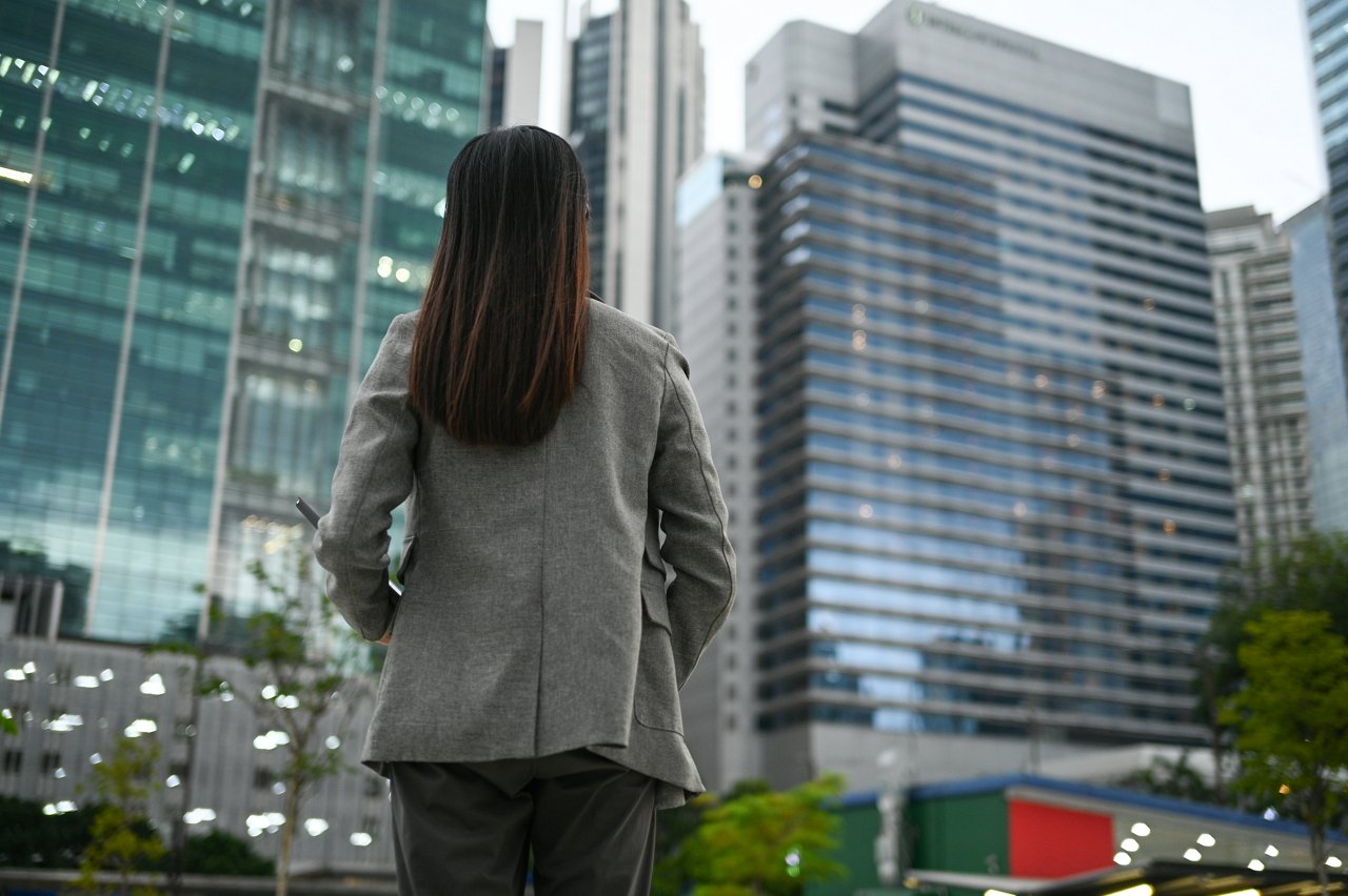 In a scene of corporate elegance, a confident businesswoman stands before the skyline, her gaze lifted toward new opportunities. The image represents ambition, empowerment, and the unbreakable spirit of female leadership in today’s business world.