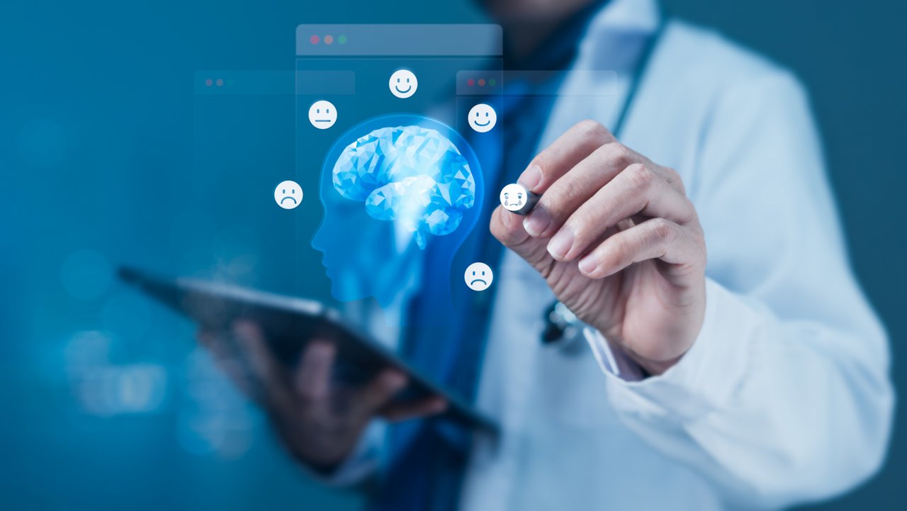 Doctor in a white coat interacts with a virtual screen showing a glowing digital brain and various emoji expressions (happy, sad, neutral), symbolizing mental health assessment and emotional well-being