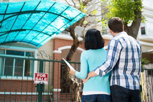 A couple looking at a house with a ‘for sale’ sign