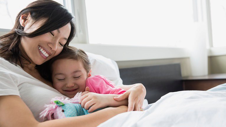 Mother and daughter hugging in bed