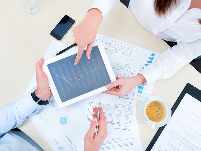 Businessman discussing with financial analyst business development strategy project and using modern digital tablet with chart on a screen. Top view photoshoot.
