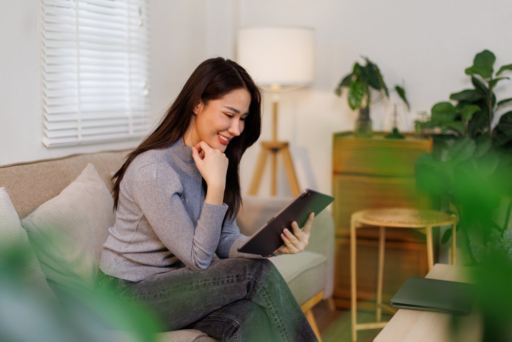 a smiling woman looking at her tablet