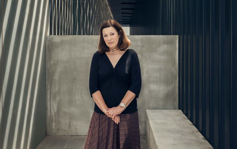 Woman standing, surrounded by architecture looking solemn