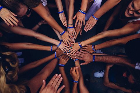 A group of people placing their hands on top of each other in a circle.