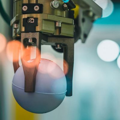 Closeup robot hand machine picking up white ball on bokeh blurred background