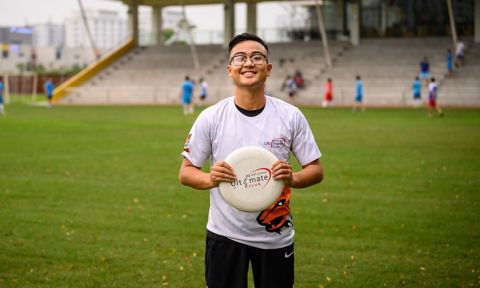 a student holding a frisbee on soccer field 