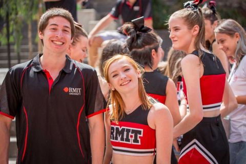 A man in an RMIT shirt stands with a woman in an RMIT cheerleading costume.