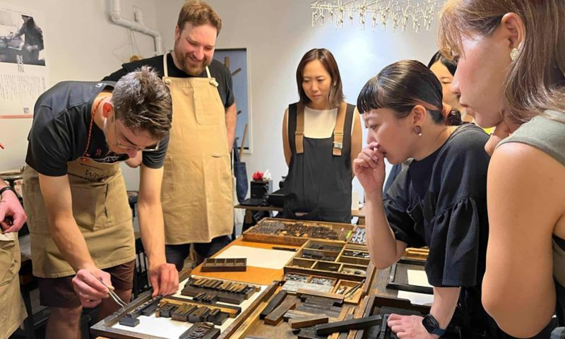 Image of a group of people standing around a table with wooden objects.