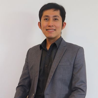 a headshot of an asian man in suit smiling 