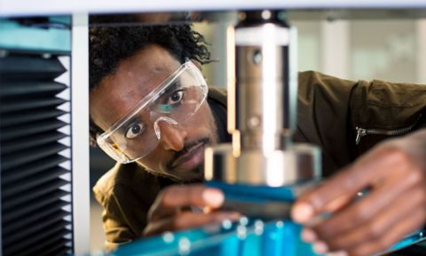 A man works on an engineering project holding an instrument with safety glasses.