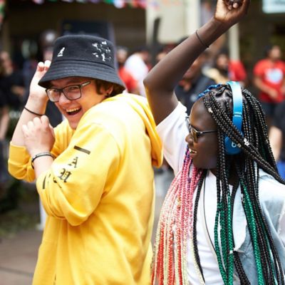 Two students dance with their arms in the air.