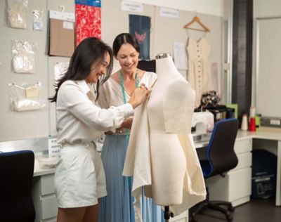 fahion-student-and-teacher-adjusting-cloth-on-mannequin