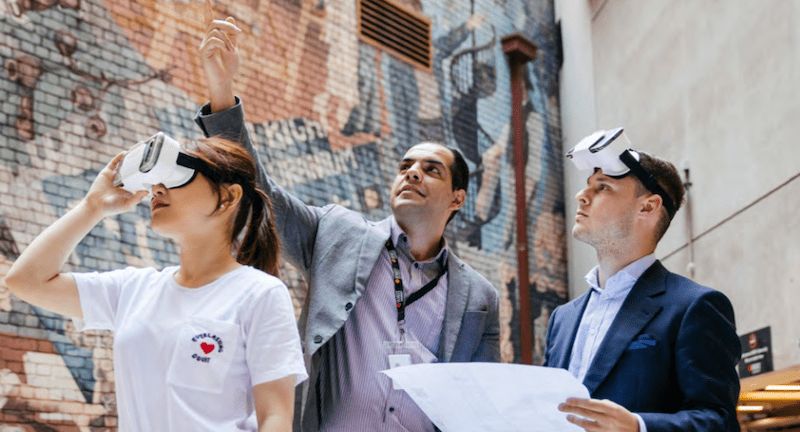 people wearing VR googles in an outdoor area with mural on brick wall in the background