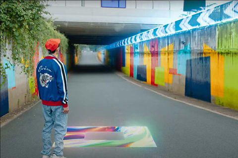  a male student standing on a street filled with graphics and colours