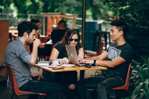 A group of students are sitting in a cafe talking to each other