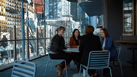  Four women seated at an outside table on the balcony of RMIT's Building 80, Swanston Street, Melbourne.