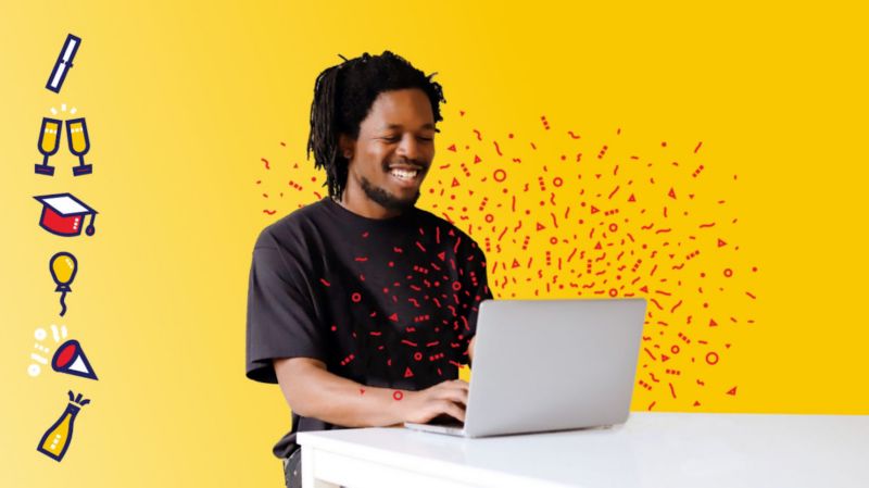 Student sitting at computer smiling in front of yellow background