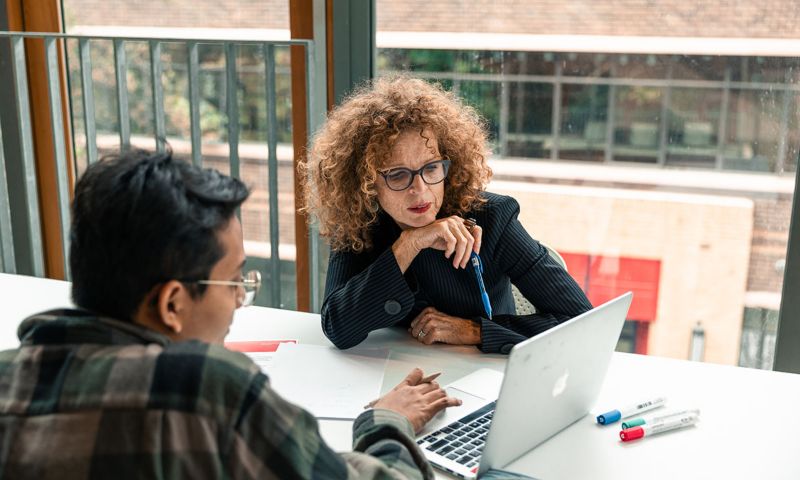 A mentor and an RMIT alumnus sit together with a laptop in discussion