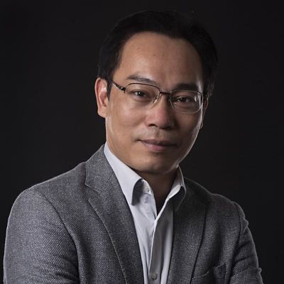 a headshot of an asian man in suit smiling 