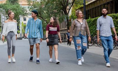 five male and female students walking through the RMIT city campus chatting to each other