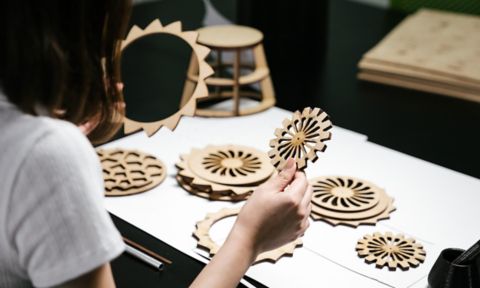 A student holds up a wooden decorative object.