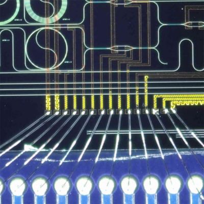 A packaged chip from the Integrated Photonics and Applications lab with electrical wire bonding and optical fiber array bonding.