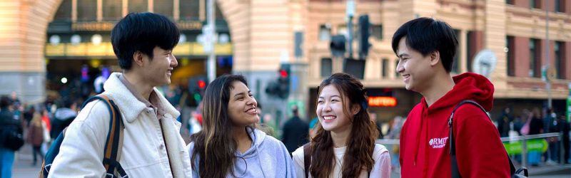 Four students standing in front of Flinders Street Station in the Melbourne CBD.