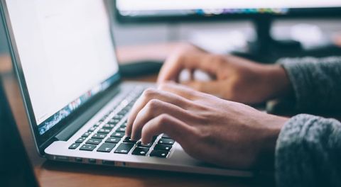 Close-up of hands typing on a laptop.