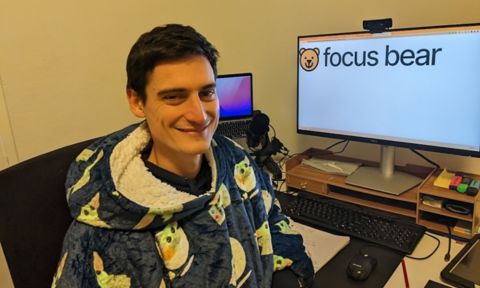 Jeremy sits in front of a computer that displays the Focus Bear logo.
