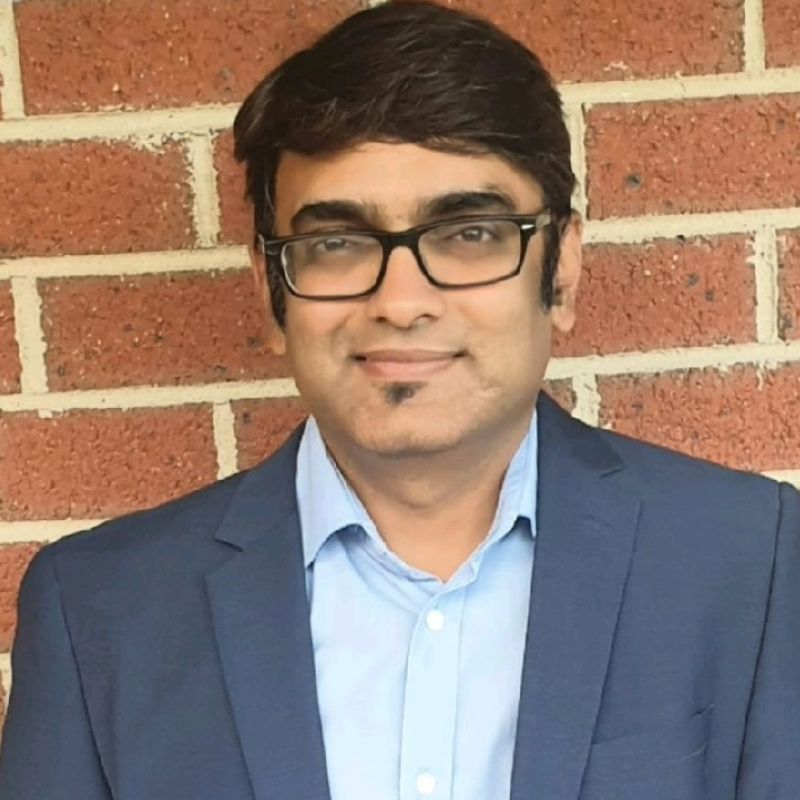 Profile photo of Kalpit Shah smiling towards the camera against a brick wall