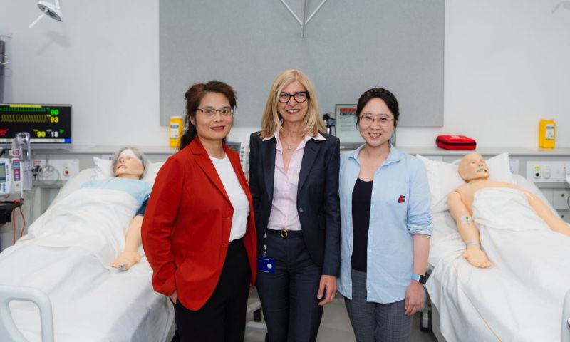 Three academics posing in front of a hospital room